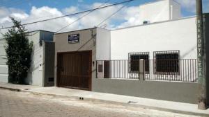 a white building with a brown door on a street at Casa no centro com 4 quartos e ar condicionado in São João Batista do Glória