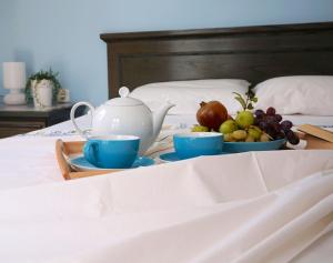 a tray with a tea pot and fruit on a bed at Cybele Apartments in Makry Gialos