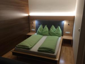 Schlafzimmer mit einem Bett mit grüner Bettwäsche und Kissen in der Unterkunft Haus Arosa in Pettneu am Arlberg