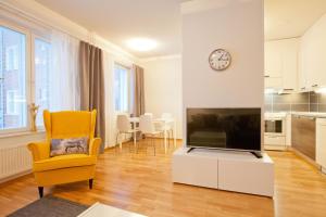 sala de estar con TV de pantalla plana y silla amarilla en Kansankatu Apartments en Rovaniemi