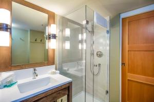 a bathroom with a shower, sink, and mirror at Sundial Hotel in Whistler