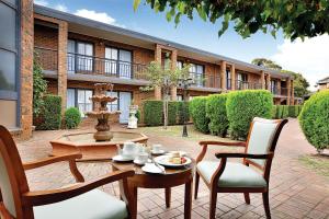 un patio con una mesa, sillas y una fuente. en Best Western Plus Buckingham International, en Moorabbin