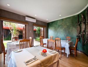 a restaurant with white tables and chairs and green walls at Singa Lodge - Lion Roars Hotels & Lodges in Port Elizabeth