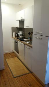 a kitchen with white cabinets and a wooden floor at Appartement Taïko in La Flèche