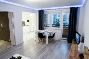 a living room with a table and chairs and a kitchen at APARTAMENT FOCUS in Gdynia