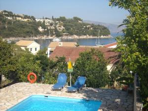 two chairs and a swimming pool with a view of the water at Villa Lemonia in Kalami