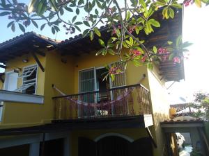 a yellow house with a balcony with flowers on it at Vila do Sossego in Cabo Frio