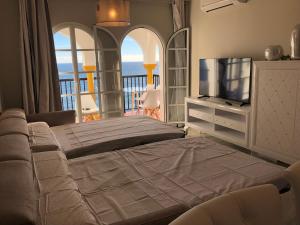 een slaapkamer met een bed, een tv en een balkon bij BALCON DEL MAR 2-3 A, APARTAMENT ON THE BEACH FRONT in La Cala de Mijas