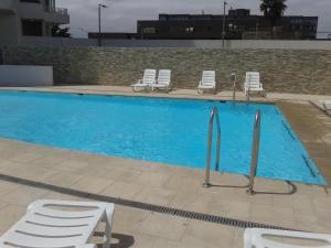 una gran piscina azul con sillas y sillas en Departamento frente al mar, en La Serena