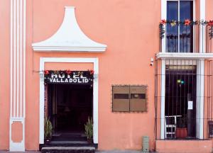 a pink building with a sign over a doorway at Hotel Valladolid in Valladolid