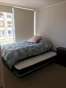 1 dormitorio con cama con almohada y ventana en Departamento perfecta ubicación Viña del Mar, en Viña del Mar