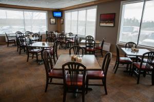 un comedor con mesas, sillas y ventanas en Deer Lake Motel en Deer Lake