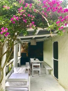 a patio with a table and chairs and pink flowers at Hus Punta Rubia in La Pedrera