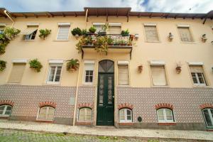 a building with a green door and a balcony with plants at Vila Berta Chez Andreia in Lisbon
