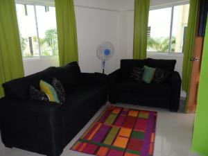 uma sala de estar com dois sofás pretos e um tapete em Apartamento Aquarel em Boca Chica