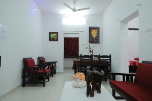 Green Garden Resort في كوتالام: غرفة طعام مع كراسي وطاولة وكلبين