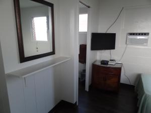 a room with a television and a desk with a mirror at Tip Top Motel in Lihue