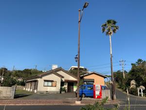 a car parked in front of a house with a palm tree at Minshuku Nodoka in Yakushima