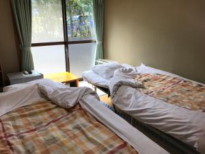 two twin beds in a room with a window at Minshuku Nodoka in Yakushima