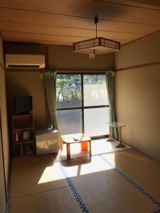 a living room with a table and a large window at Minshuku Nodoka in Yakushima