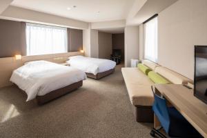 um quarto de hotel com duas camas e uma televisão de ecrã plano em JR Clement Inn Takamatsu em Takamatsu