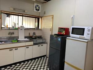 a kitchen with a microwave on top of a refrigerator at Minshuku Nodoka in Yakushima