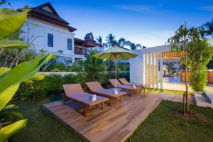 a wooden deck with chairs and an umbrella at Villa Palavee (A2) in Ao Nang Beach