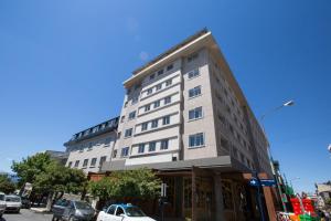 a tall white building on a city street with cars at Hotel Sol Bariloche in San Carlos de Bariloche