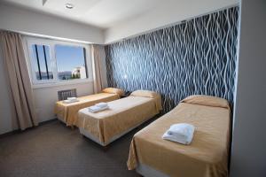 a hotel room with two beds and a window at Hotel Sol Bariloche in San Carlos de Bariloche