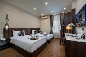 a hotel room with two beds and a desk at Splendid Pearlight Hanoi in Hanoi
