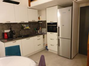 a kitchen with white cabinets and a refrigerator at Résidence azur sancy in Le Mont-Dore