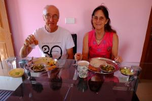 Ein Mann und eine Frau sitzen an einem Tisch mit Teller Essen. in der Unterkunft Suma Guest House in Bodh Gaya