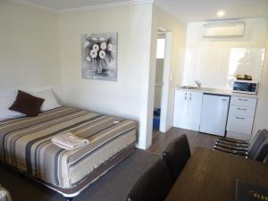 a small bedroom with a bed and a kitchen at Centrepoint Motel in Dubbo