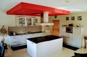 a kitchen with white cabinets and a red ceiling at Villa Tomasso in Eeklo