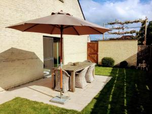 een tafel met een paraplu in een tuin bij Villa Tomasso in Eeklo