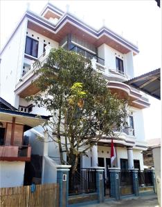 uma casa branca com uma árvore em frente em Toraja Lodge Hotel em Rantepao