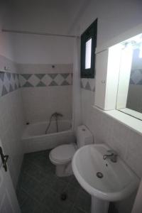 a white bathroom with a sink and a toilet at UMBRELLA BEACH APARTMENTs in Kavos