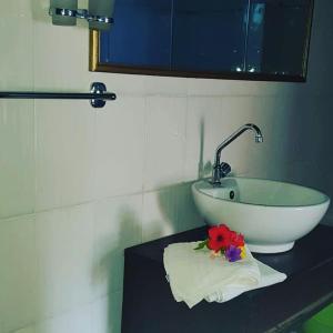 baño con lavabo y flores en una mesa en Rocks villa homestay, en Galu