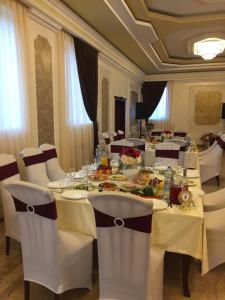 a dining room with a long table with white chairs at Hotel Ershov in Ishim