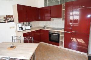 eine Küche mit roten Schränken und einem Tisch darin in der Unterkunft Ferienhaus am Hutberg in Großschönau