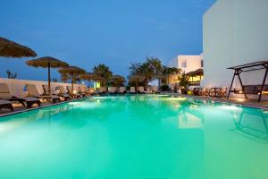 une grande piscine avec des chaises et un hôtel dans l'établissement Alexandra Hotel, à Kamari