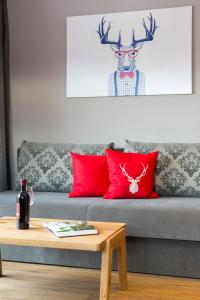 a living room with a couch with red pillows and a deer head at Das Grünholz Aparthotel in Mühlbach am Hochkönig