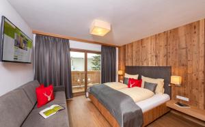 ein Schlafzimmer mit einem Bett und einem Sofa in der Unterkunft Das Grünholz Aparthotel in Mühlbach am Hochkönig
