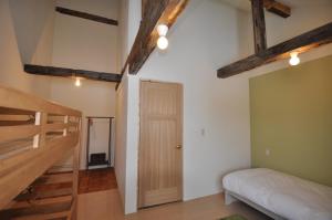 a room with a bed and a staircase with wooden beams at Gufo no Mori Kamifurano in Kami-furano