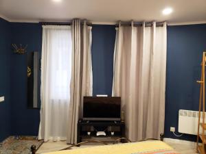 una camera da letto con pareti blu, tende bianche e TV di Lucky Apartment a Tbilisi City