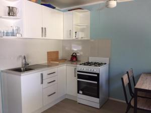 a kitchen with white cabinets and a stove and a table at Elouera Units in Fraser Island