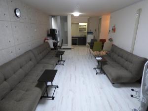 una sala de espera con sofás, mesas y sillas en カメリア府中202号室 en Fuchu