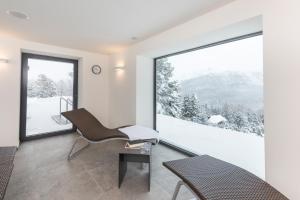 Zimmer mit einem Stuhl und einem großen Fenster in der Unterkunft Berghotel Randolins in St. Moritz