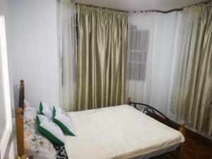 a bed with white sheets and pillows in a bedroom at Juliet Guest House near Enchanted Kingdom in Balibago