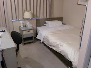 Habitación de hotel con 2 camas y escritorio con lámpara. en Tsuyama Central Hotel Annex en Tuyama